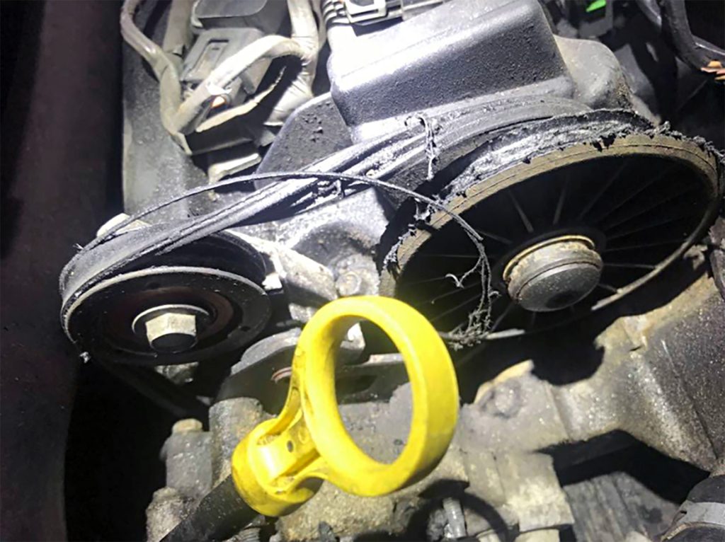 Shredded drive belt and drive pulley on a Cadillac.