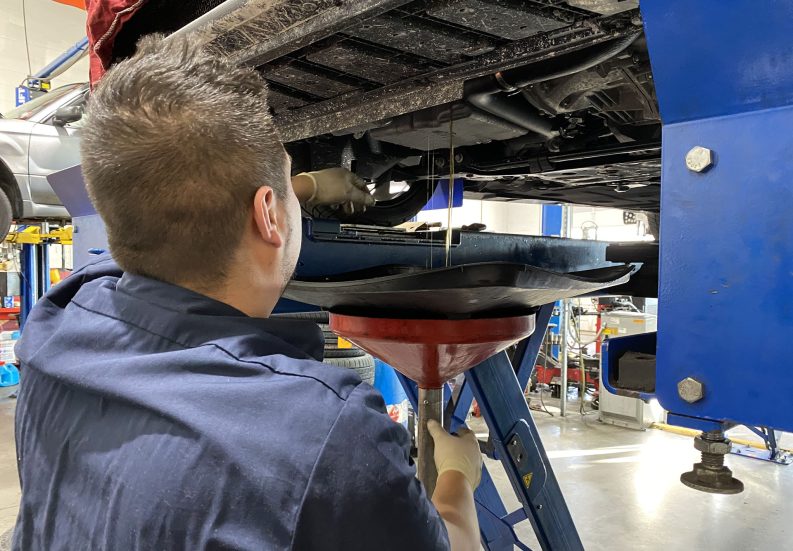 Technician performing oil change at HomeTowne Auto Repair.